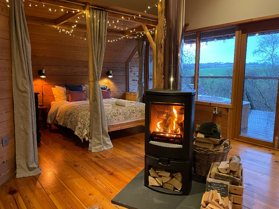Interior of treehouse showing beautiful 4 poster bed and woodburner
